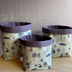 three storage bins sitting on top of a wooden table