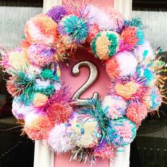 a colorful wreath with the number two on it is hanging in front of a pink door