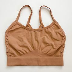 a cropped top with holes on the front and straps at the back, sitting on a white surface