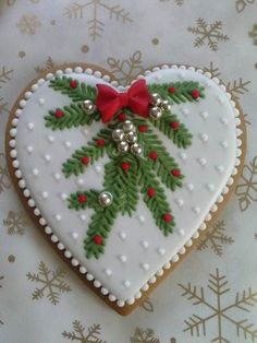 a decorated cookie in the shape of a heart with holly leaves and bells on it