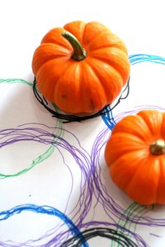 three small pumpkins sitting on top of a white paper with colored circles around them