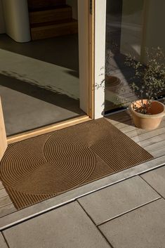 a door mat sitting on top of a wooden floor next to a potted plant