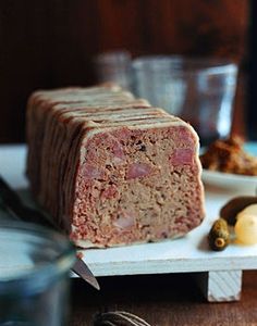 a piece of meatloaf sitting on top of a cutting board next to other food