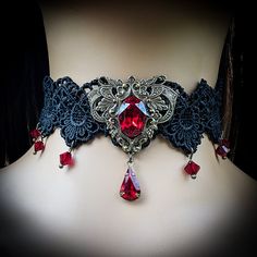 "This vintage gothic styled crystal choker necklace features captivating Siam Red Swarovski crystals with nice crisp facets and brass embellishments.  The detailed stampings have been in production since the 1940's and the vintage 16x11mm focal crystal is no longer in production, making this necklace a rare find.  The lace is double-layered and hand sewn together for extra durability. Both elegant and stylish, this piece would be perfect for any formal occasion. Swarovski Crystals are made in Austria and are the highest quality lead free glass-cut crystals on the market, with extra facets and gold foiling for outstanding brilliance and sparkle. The choker lace is 12.5\" long and includes a 3\"extension chain, totaling 15.5\" of length.  A pretty gold colored star hangs down from the chain Gothic Costume Jewelry Choker, Red Gothic Jewelry For Party, Elegant Costume Jewelry Choker, Elegant Red Jewelry For Halloween, Formal Gothic Metal Choker, Gothic Crystal Jewelry For Gift, Silver Vampire Style Choker As Gift, Steampunk Choker Jewelry Gift, Fantasy Red Jewelry For Party