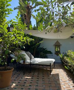 a patio with a chaise lounge and potted plants on the side, surrounded by greenery