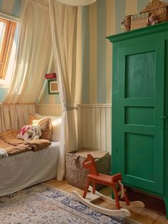 a room with a bed, rocking chair and green cabinet