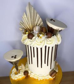 a cake decorated with white frosting and chocolate decorations on a gold plated stand