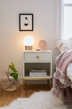 a white nightstand sitting next to a bed in a bedroom