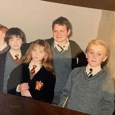 a group of young boys and girls standing next to each other in front of a piano