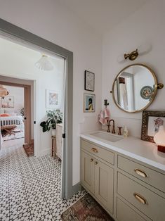 a bathroom with a sink, mirror and pictures on the wall next to it's door