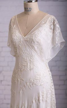 a white wedding dress on a mannequin with a brick wall in the background