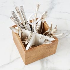 a wooden box filled with silverware on top of a white marble counter