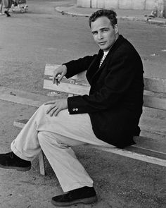 black and white photograph of a man sitting on a bench