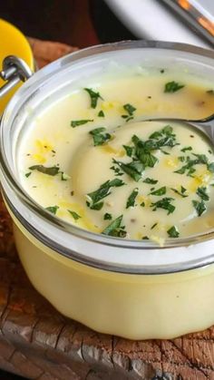 a close up of a bowl of soup on a wooden board with a spoon in it