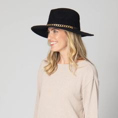 Introducing Jolene - the epitome of sophistication. Crafted from a luxurious wool blend, this fedora features a front gold chain and a faux leather band in the back. Its 3.5" brim size will keep you stylish and protected. Available in elegant black. Features: Color: Black Material: 60% Wool, 40% Polyester Size: 57cm Machine Knit Wool Blend Fedora Front Gold Chain and Back Faux Leather Band Brim Size: 3.5" Chic Fedora With Flat Crown For Formal Occasions, Chic Formal Fedora With Flat Crown, Chic Fedora Hat Bands For Winter, Chic Fedora Felt Hat For Party, Chic Evening Fedora Felt Hat, Gold Fedora Hat For Winter, Chic Felt Fedora Hat, Chic Brimmed Hat As Fashion Accessory, Chic Formal Hat Band With Flat Crown