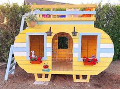 a yellow and white house made out of pallet wood with plants on the roof