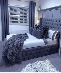 a bedroom with grey walls and carpeted flooring has a large bed with gray headboard and foot board