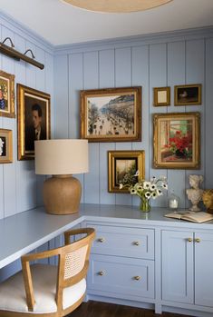 a room with blue painted walls and pictures on the wall, along with a desk