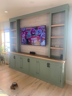 a flat screen tv sitting on top of a wooden entertainment center in a living room