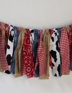 a red, white and black cow print scarf hanging from a line on a wall