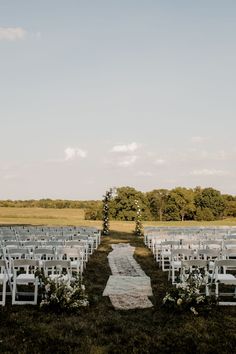 an outdoor ceremony setup with white chairs and flowers