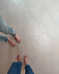 two people are standing on the floor with their feet in the air and one person is wearing blue jeans