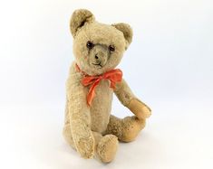 a brown teddy bear with an orange bow tie