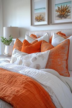 an orange and white bed in a bedroom with pictures on the wall above it,