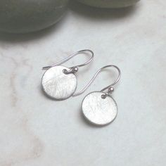 Simple minimal earrings, made from brushed stainless steel discs and sterling silver earwires.  The earrings dangle about 2,3 cm ( 0.9 inches) from top of ear wire to bottom of disc. Size of disc is 12 mm. Materials: stainless steel, sterling silver  All pieces are made by hand in my studio, with love and care   Your jewelry arrives in a lovely package, perfect for gift giving  Please contact me if you have any questions. Simple Round Silver Earrings, Simple Circle Nickel-free Earrings, Modern Silver Round Disc Earrings, Modern Nickel-free Round Disc Earrings, Simple Silver Nickel-free Earrings, Modern Sterling Silver Round Disc Earrings, Minimalist Silver Round Pendant Earrings, Minimalist Sterling Silver Round Disc Earrings, Minimalist Cadmium-free Sterling Silver Earrings