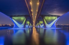 the underside of a large bridge over water at night