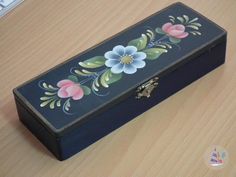 an empty black box with flowers painted on it sitting on a wooden table next to a computer