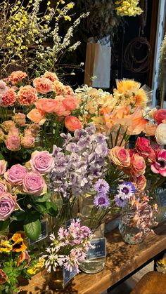 many different types of flowers in vases sitting on a table with other flowers behind them