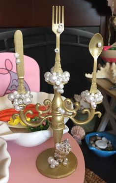 there is a gold candle holder with forks and spoons on top of the table