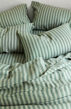 an unmade bed with green and white striped sheets