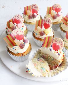 cupcakes with white frosting and colorful toppings are arranged on a plate