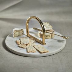 some crackers and cheese are on a marble platter with a golden metal handle