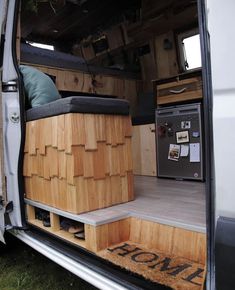 the interior of a van with its door open and wooden furniture in the cargo area