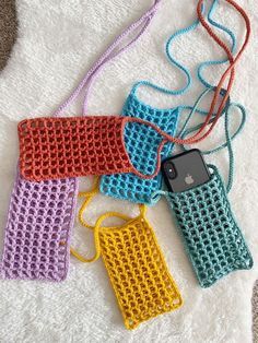 four crocheted cell phones are laying on a white towel and one has a phone in it