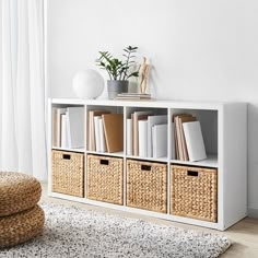 a white shelf with wicker baskets and books