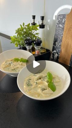 two white bowls filled with food on top of a table