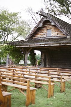 an old wooden church with benches in front