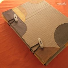 an open notebook with a computer mouse on it sitting on top of a bed covered in orange sheets