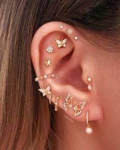 a woman's ear is adorned with gold butterflies and pearls