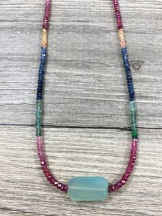 "A beautiful sky blue faceted slab shaped chalcedony is centered on a glimmering strand of multicolored sapphire rondelles.  Sapphires set off a gorgeous rainbow of colors, including red, pink, yellow, green and blue.  Finished with a gold filled lobster clasp. A unique piece of jewelry from La Vie en Rose Jewelry Collection.  Necklace measures 16 3/4\" L and chalcedony slab is approx. 1\"  All jewelry comes in a natural cotton muslin drawstring bag.  Perfect for gift giving! Add more beauty to your life!" Spiritual Multicolor Faceted Necklace, Multicolor Agate Crystal Necklace With Faceted Beads, Blue Rondelle Natural Gemstones, Bohemian Faceted Rondelle Necklace, Bohemian Rondelle Faceted Necklace, Sapphire Gemstone Rondelle Necklace, Multicolor Agate Jewelry With Faceted Beads, Multicolor Faceted Gemstones For Healing, Blue Beaded Briolette Gemstone Necklace