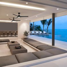 a living room filled with furniture next to a large glass window overlooking the ocean and beach