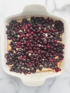 blueberry cheesecake in a casserole dish on a marble counter top with berries