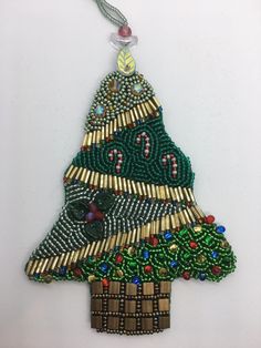 a beaded christmas tree ornament hanging on a wall