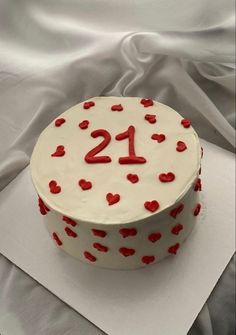 a white cake with red hearts on it and the number twenty one is decorated in red icing