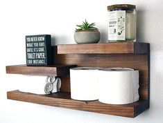 two wooden shelves holding toilet paper and a potted plant