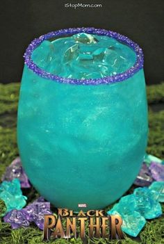 a blue drink with purple sprinkles on the rim and green grass around it